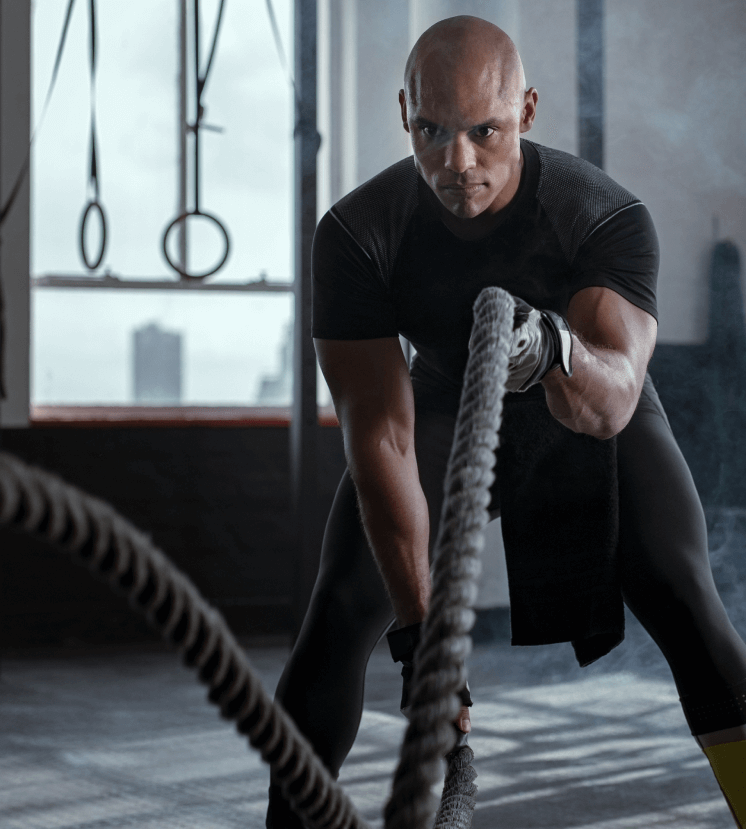 focussed man in a gym using battle ropes